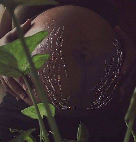vergetures dorées enceinte femme derrière une plante